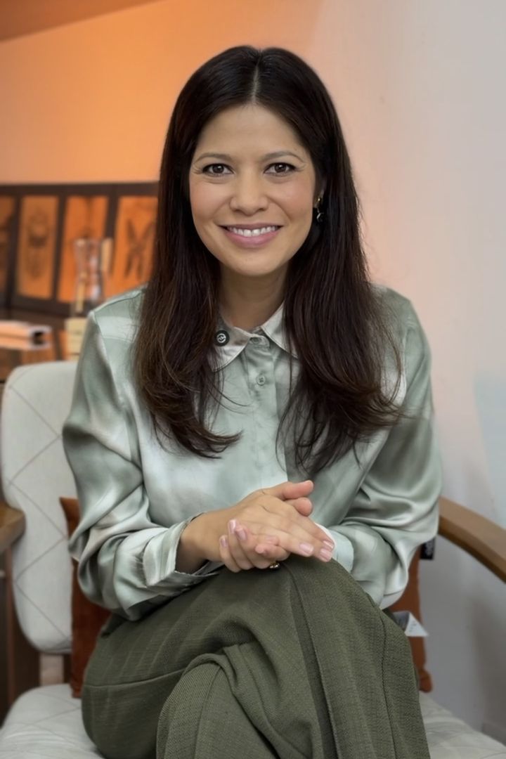 Dra. Juliana Yumi sorrindo, sentada numa poltrona, de camisa verde-clara