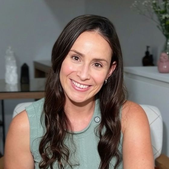Dra. Amanda Fernandes sorrindo, sentada numa poltrona, com blusa verde-sálvia