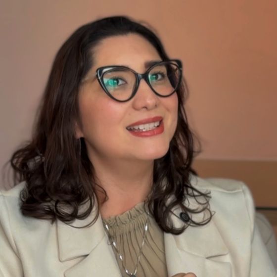 Dra. Angela Mori sorrindo, de óculos e blazer claro